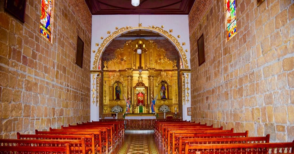 Catholic church interior with the altar and gilded retablo seen down the center aisle